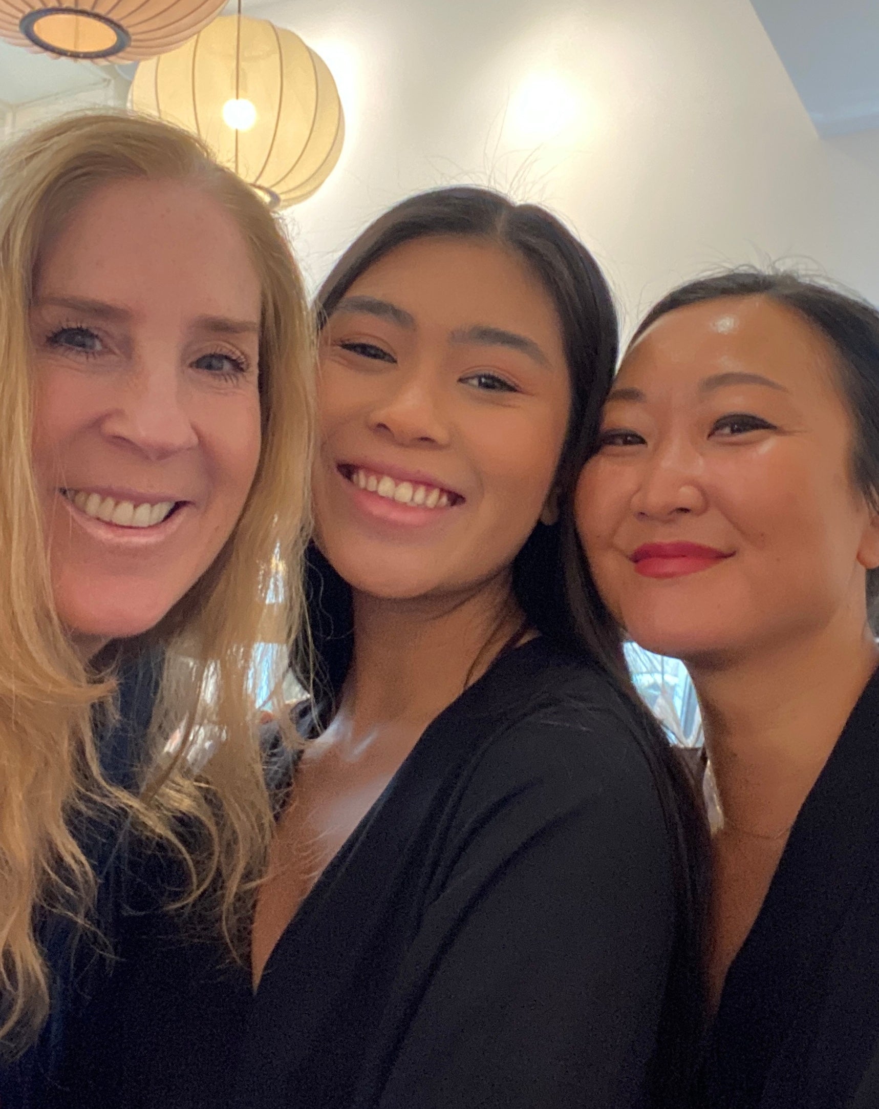 Group photo of the AWAN team. Three women are smiling and posing together indoors under decorative lamps. Anette Miwa Dimmen is on the right, next to two other team members.