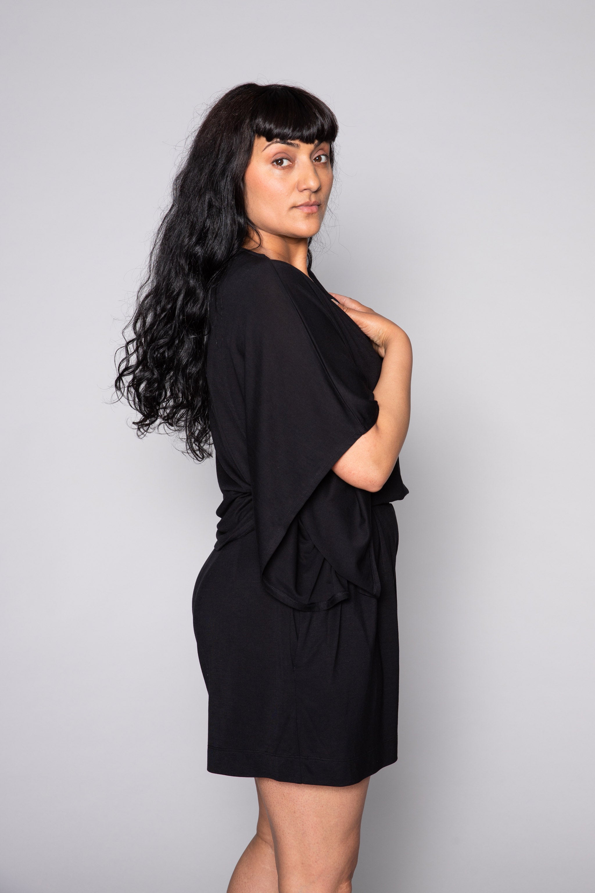 Side profile of a model wearing the AWAN Kaftan Top in warm black.